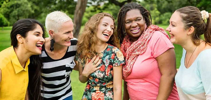 Group of five diverse friends laughing outdoors highlighting women’s reproductive health.