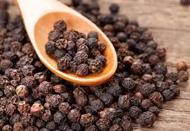 Black peppercorns in a wooden spoon highlighting their health benefits and nutrient absorption