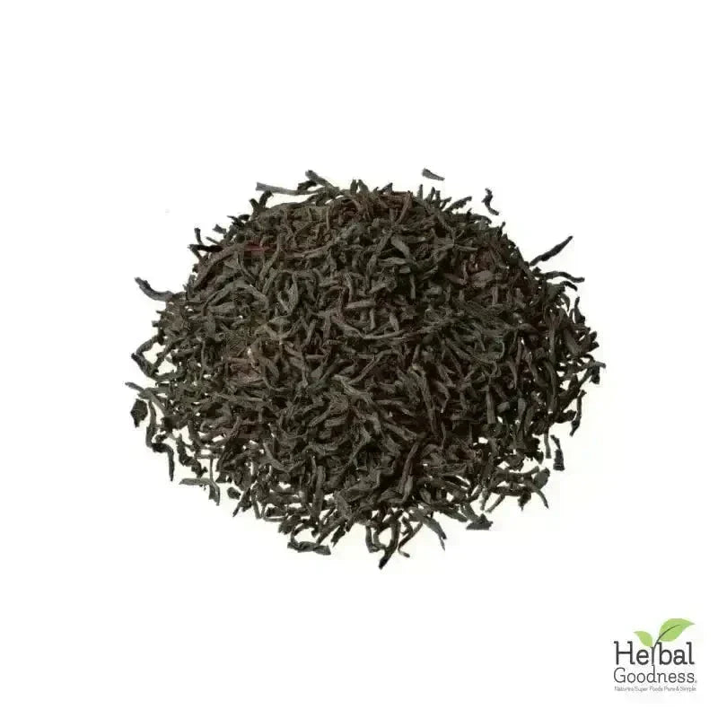 A pile of dark curly black tea leaves in organic 4oz bags for bulk herbs roots including witch hazel leaf and burdock root