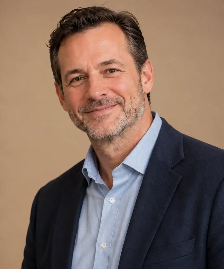A man wearing a navy blue blazer over a light blue button-down shirt.