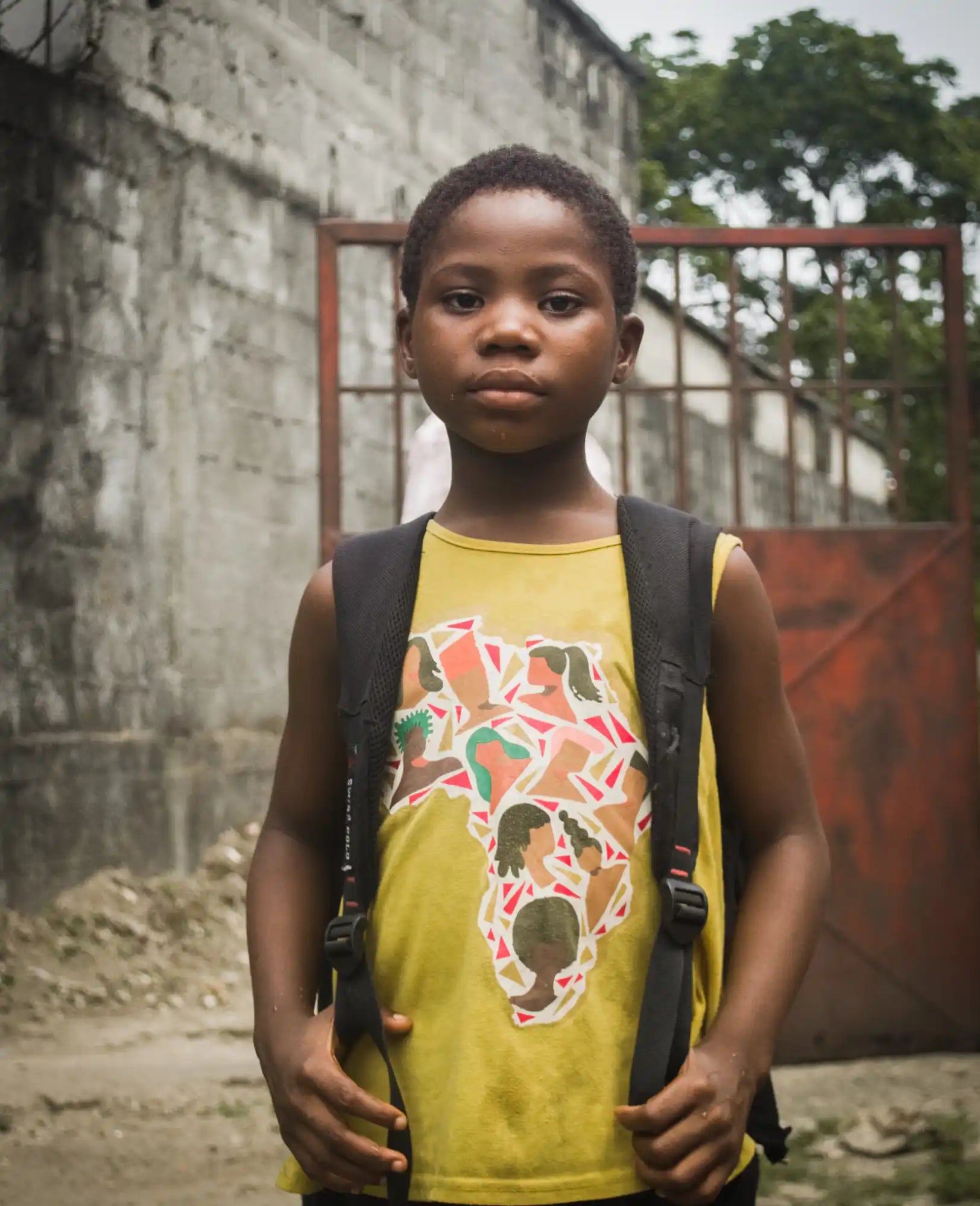 A student wearing a yellow tank top and black backpack.